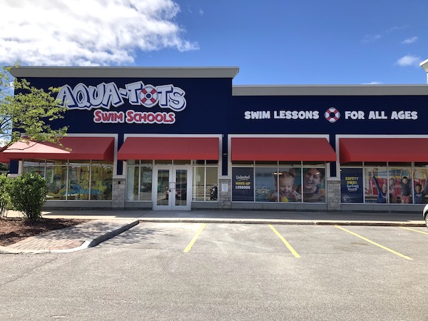 The blue and red storefront exterior of Aqua-Tots Swim Schools in Kanata, with red awnings over the entrance and windows.